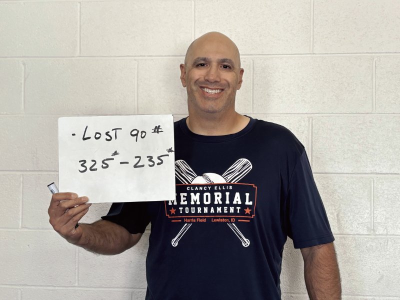 Adolfo holding a whiteboard with his weight-loss progress