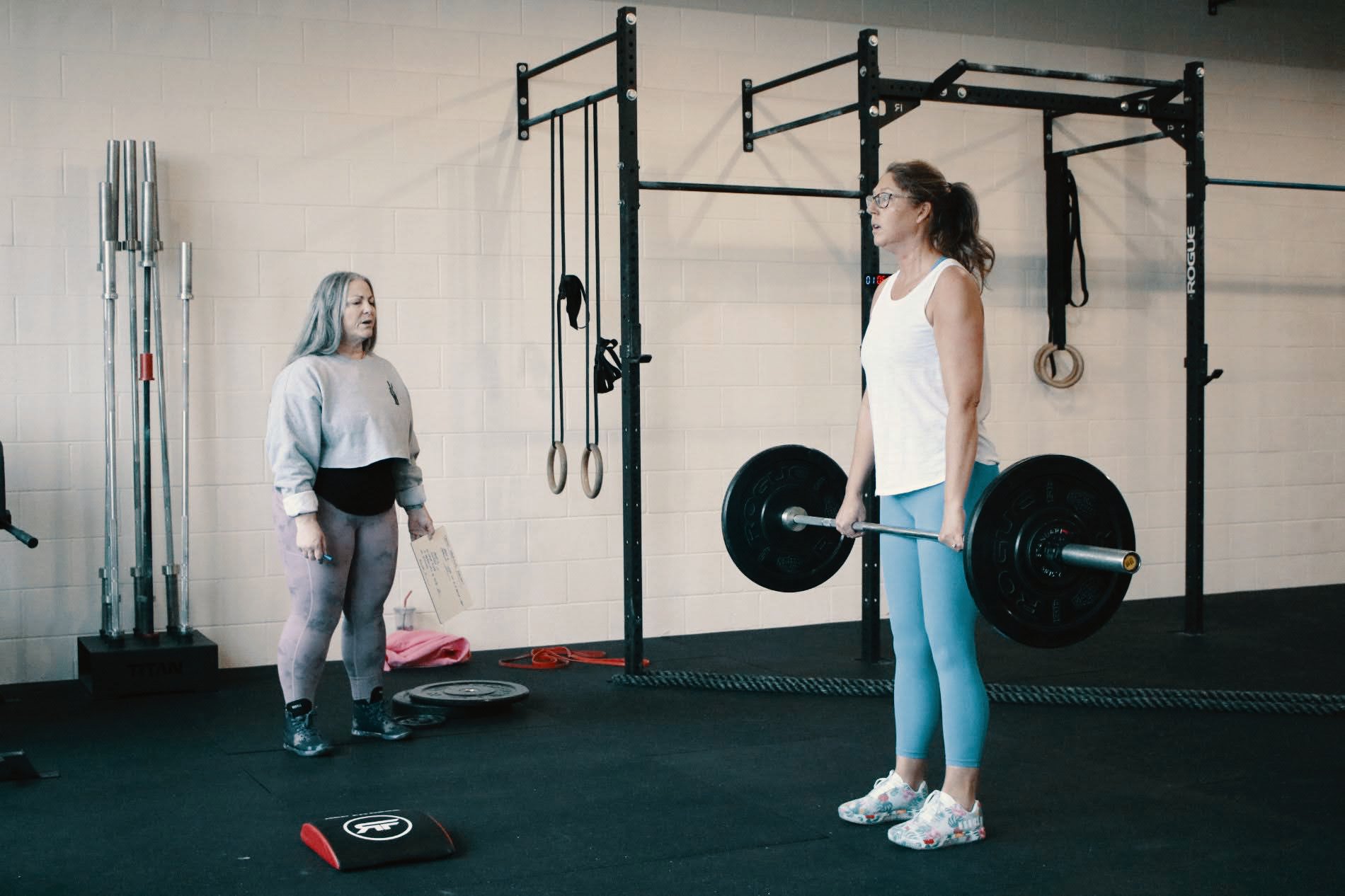 Coach and member training with a barbell at Timber & Steel